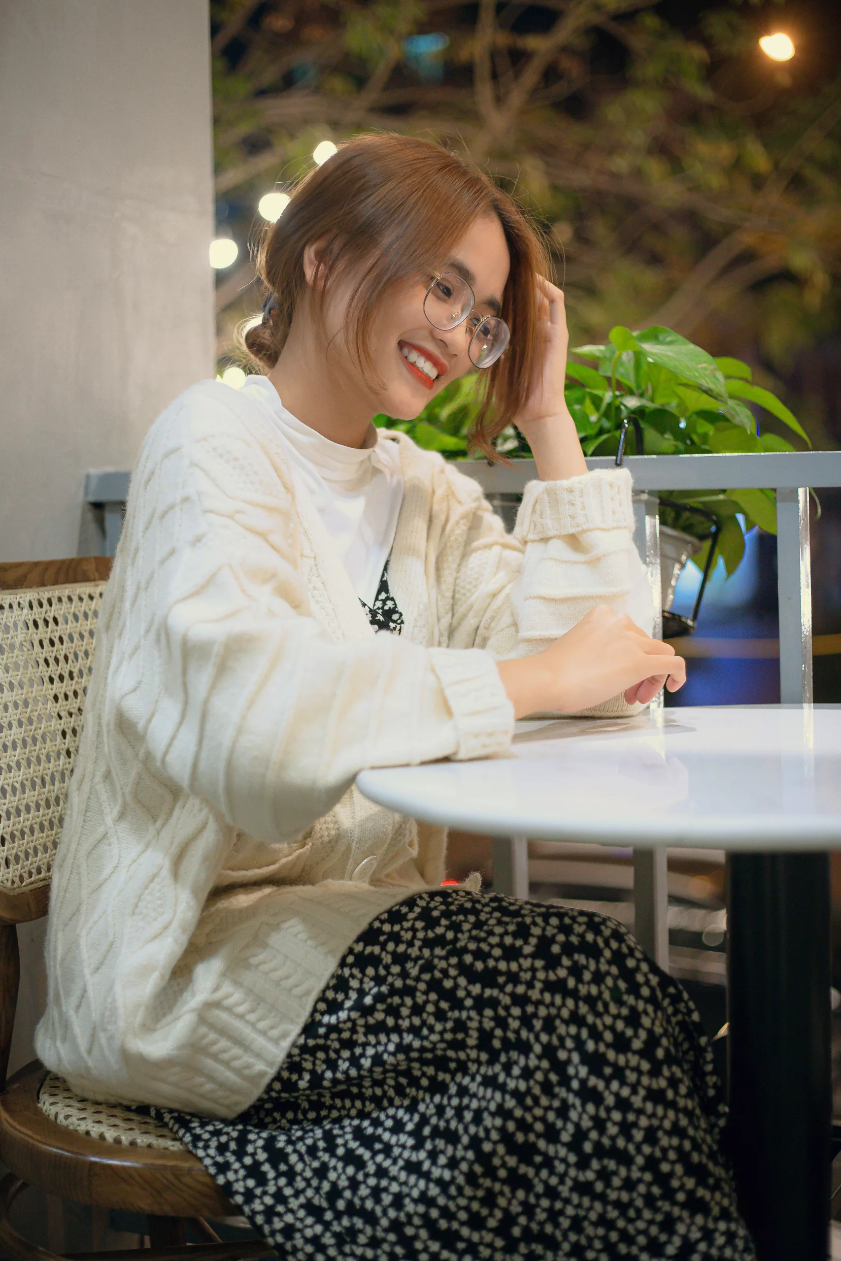 Une personne souriante consulte ses réservations de location sur une tablette, assise confortablement dans un café lumineux.