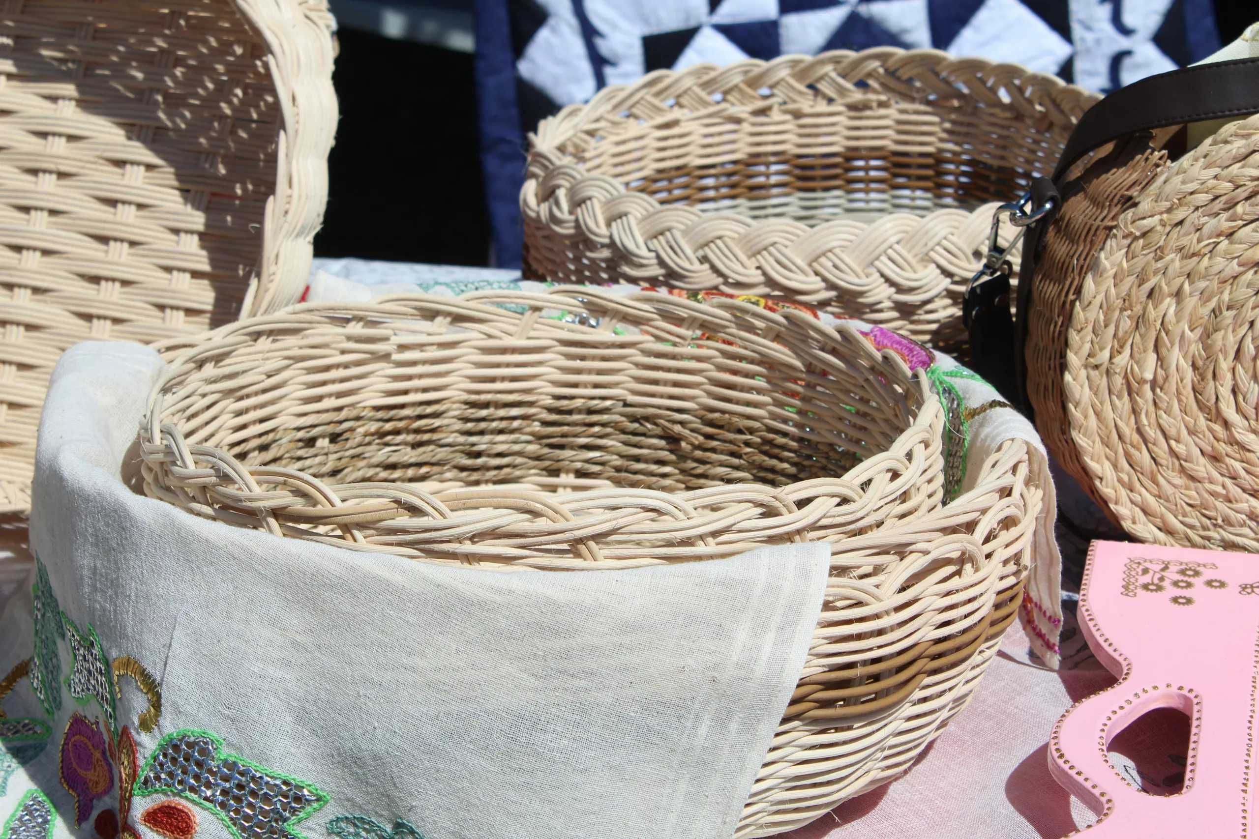 Une pile de linge de lit blanc fraîchement lavé et plié dans un panier en osier, évoquant la propreté et le service hôtelier.