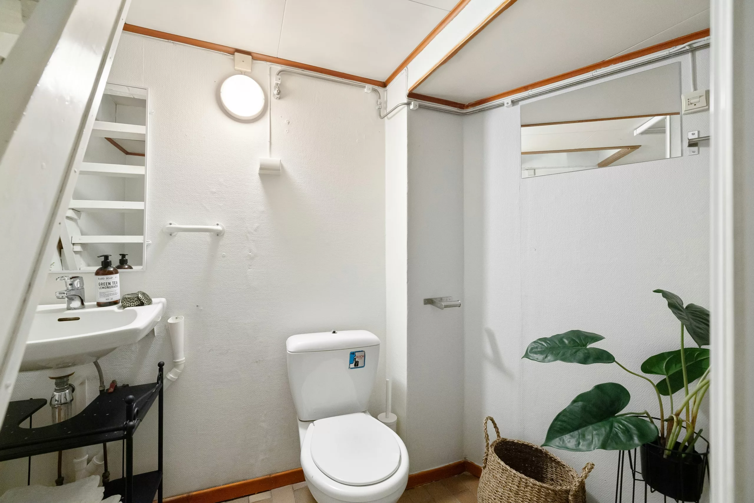 High quality photo of a modern, clean apartment bathroom maintained by cleaning staff, showing folded towels and hygiene products in a Japandi style.