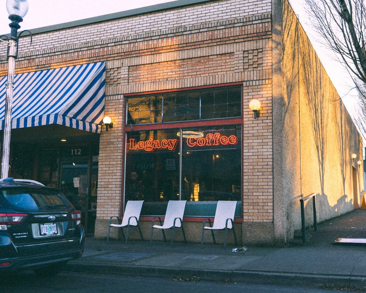 A storefront with a striped awning and three chairs.