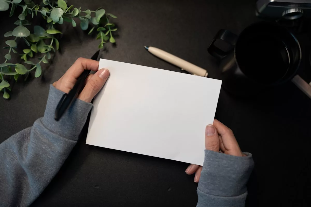 Hands holding blank card with pen and plant