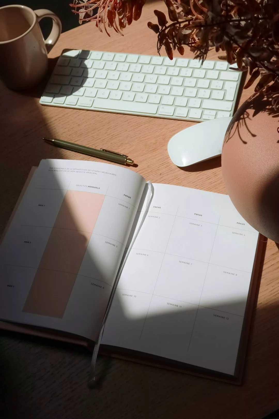 Une personne assise à un bureau, regardant par la fenêtre avec un air pensif, un calendrier et un carnet ouverts devant ...