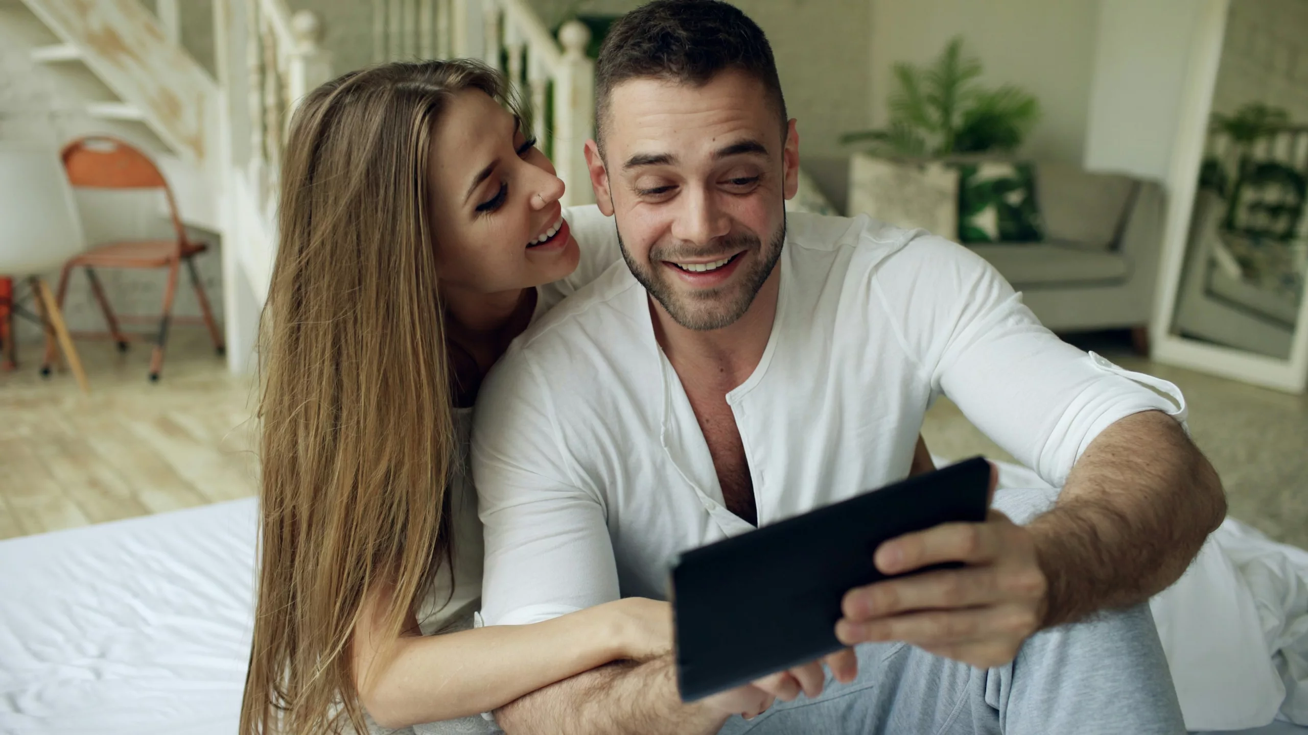 Jeune couple heureux examinant un tableau de bord de revenus locatifs sur une tablette.