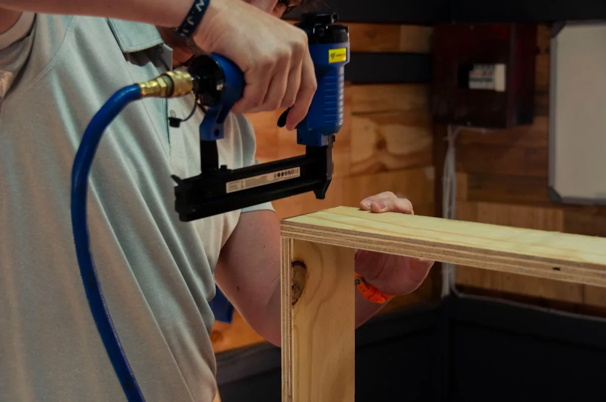 Un homme utilisant une perceuse électrique sur un morceau de bois.