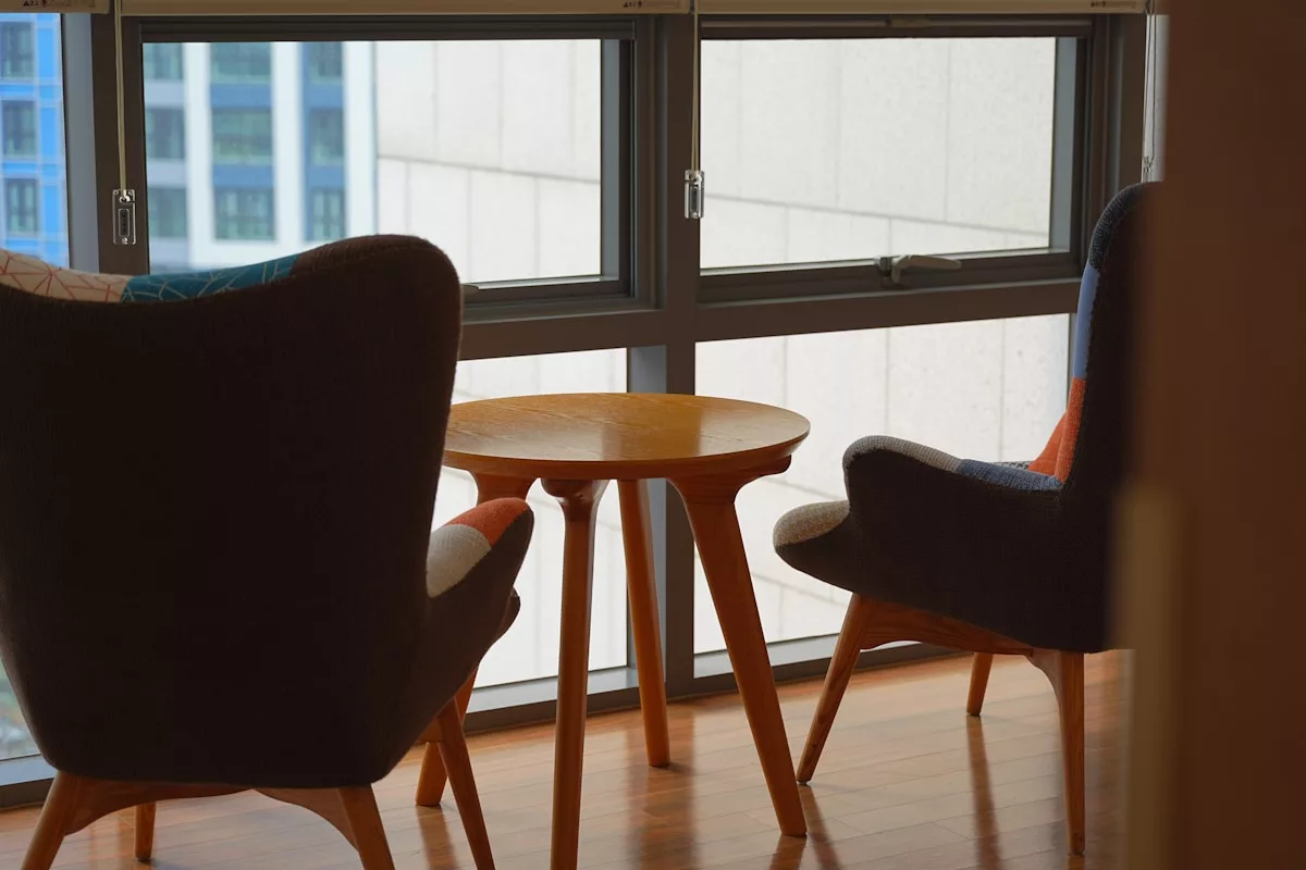 Salle de séjour confortable avec fauteuils et table basse en bois.