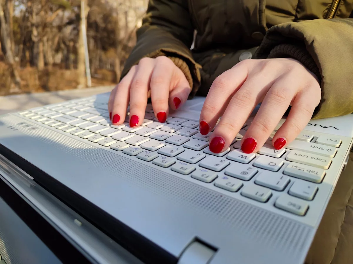 Mains féminines avec vernis rouge sur un clavier d'ordinateur portable.